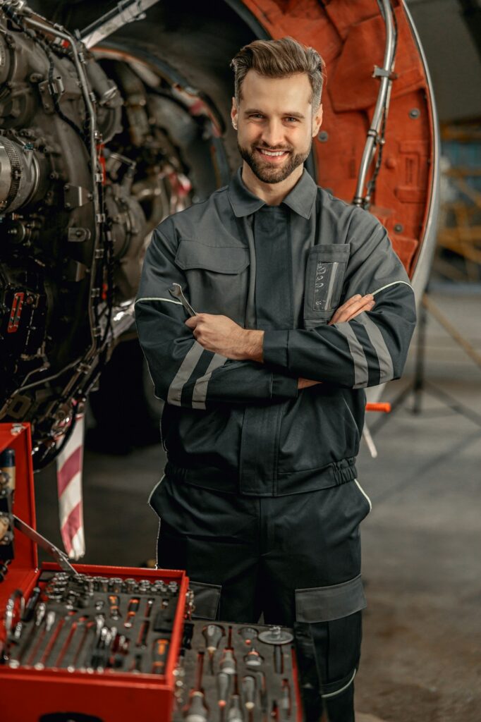 cheerful aircraft mechanic standing near tool box in hangar 1